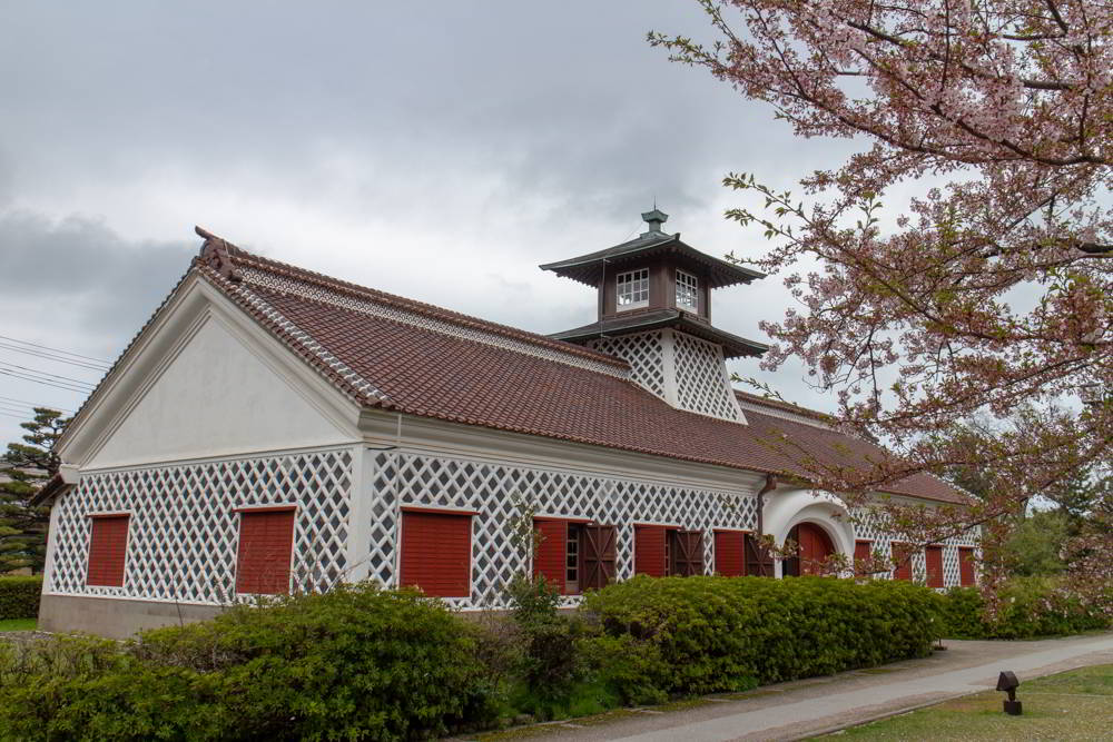 Das historische Zollhaus in Niigata mit blühenden Kirschbäumen im Vordergrund.