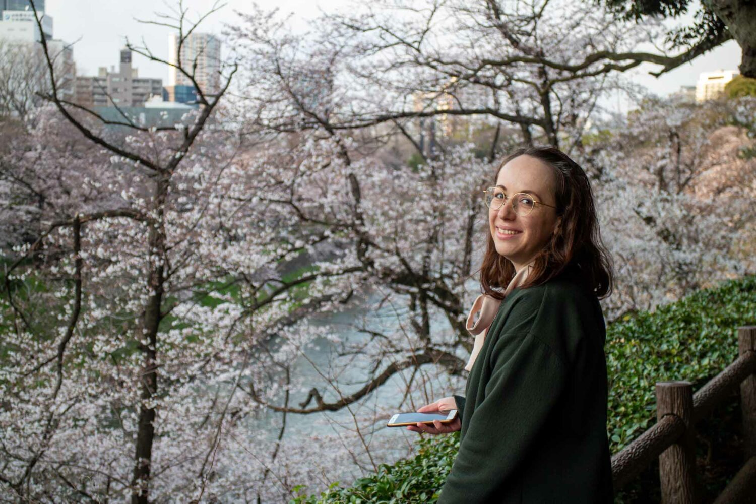 Stephanie mit Handy vor Kirschblüten