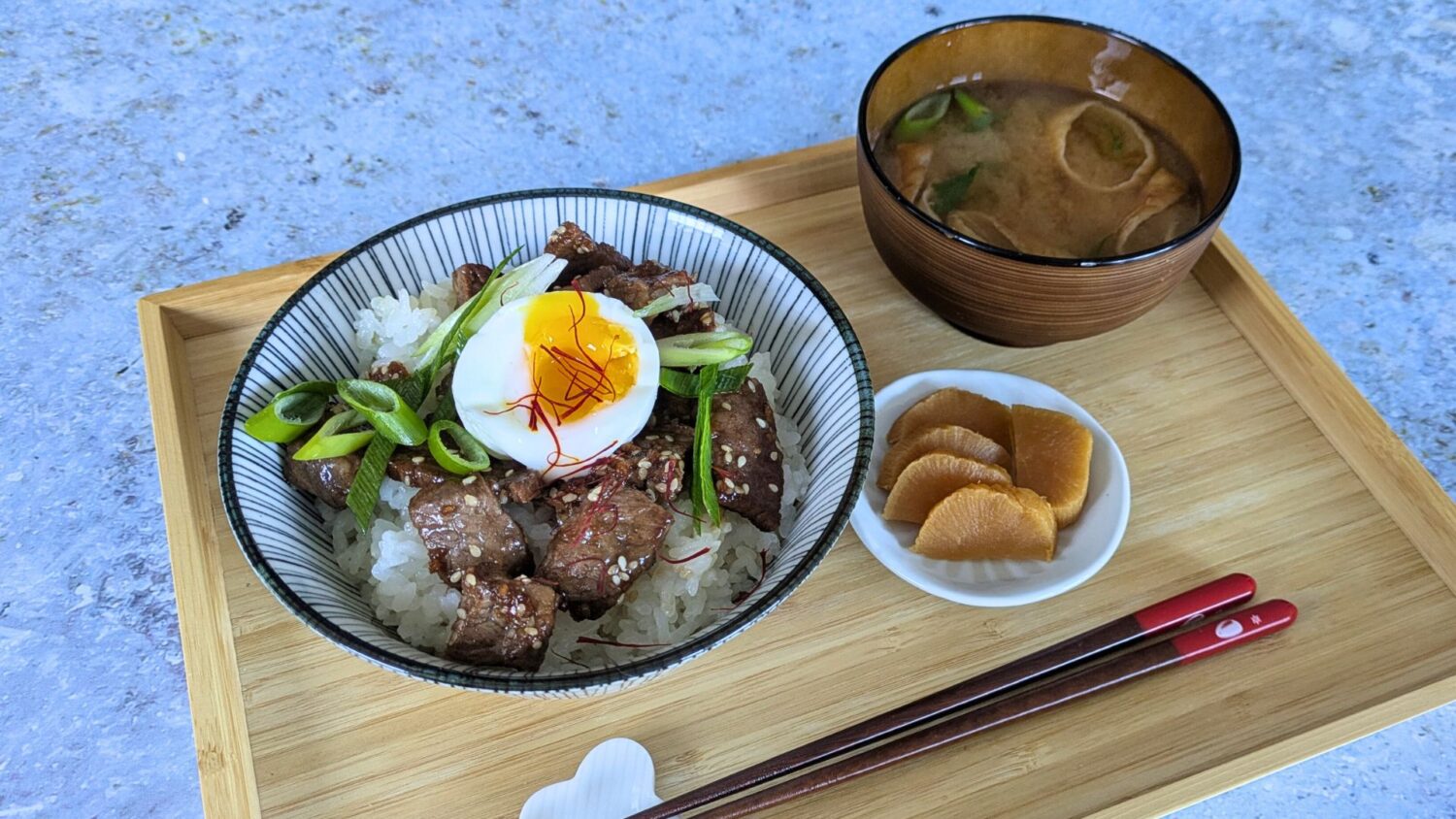 Tablet mit einer Schale Reis mit Fleisch und ein Ei und Lauch. Daneben eine Schale Miso-Suppe