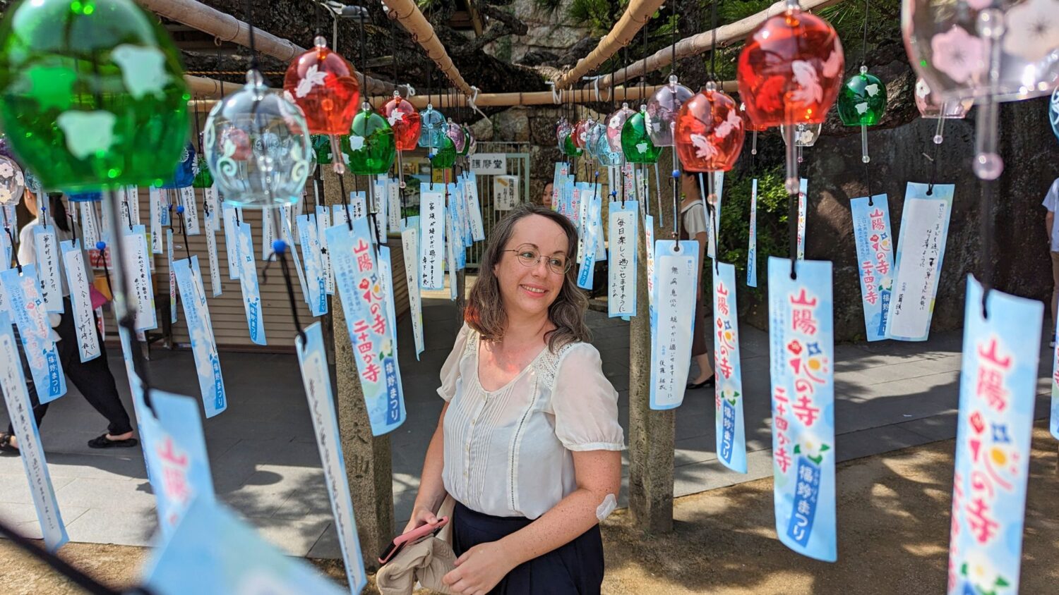 Frau stehend zwischen Windspielen auf einem japanischen Tempelgelände